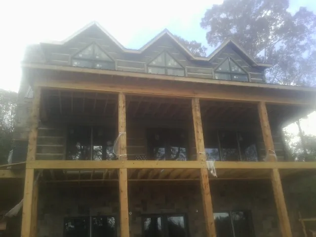 Dormers and porch framing on a large log home under construction — Roof Coating work by our crew in Kenbridge