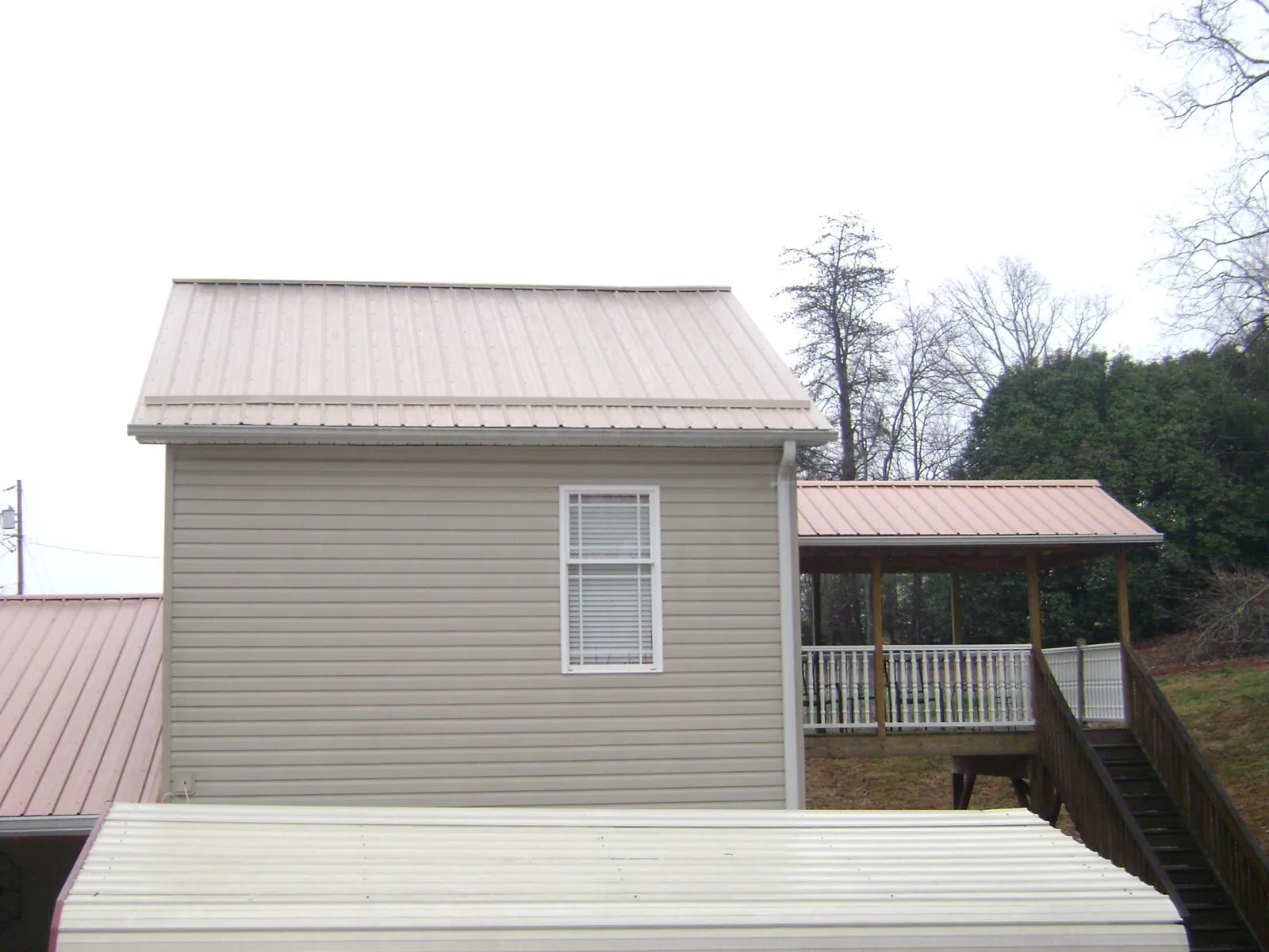 Tan metal roofs on a two story addition and attached porch, from a Roof Replacement job in Kenbridge
