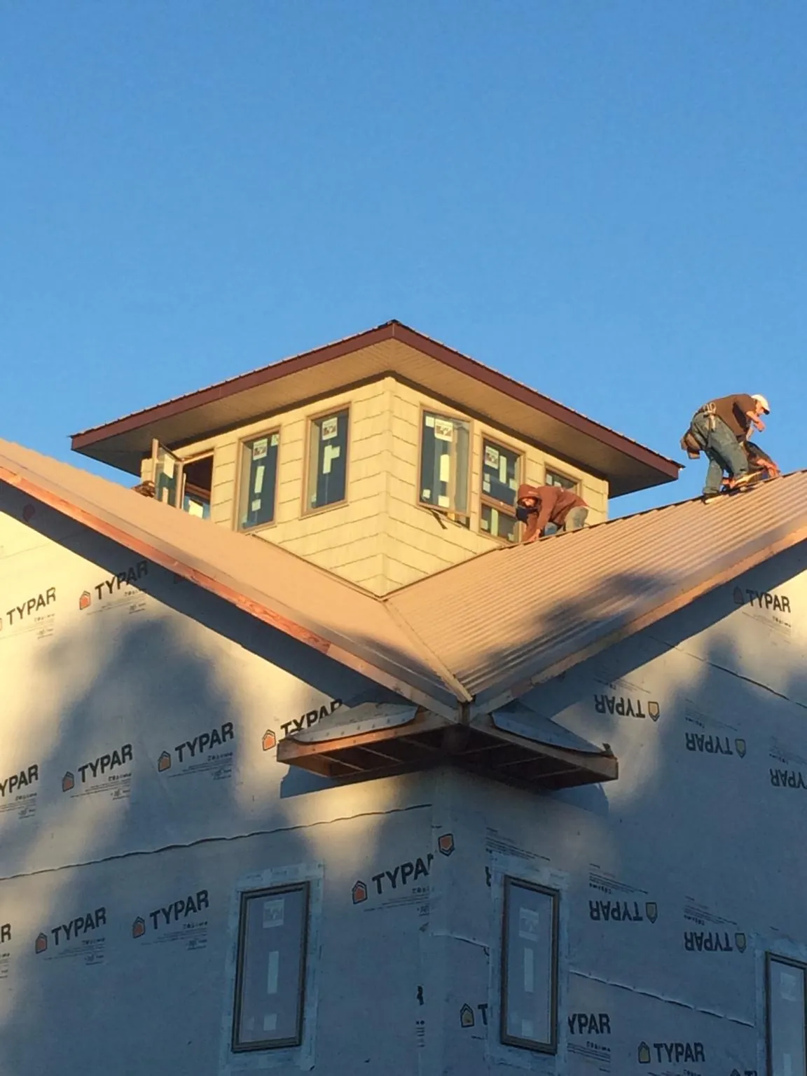 Roofers working around a rooftop cupola on a new metal roof at sunset — Roof Waterproofing in Kenbridge by Roofing Brothers